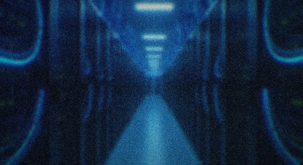 Dim data-center hall, long rows of server racks, glowing blue/cyan cable runs down a receding aisle