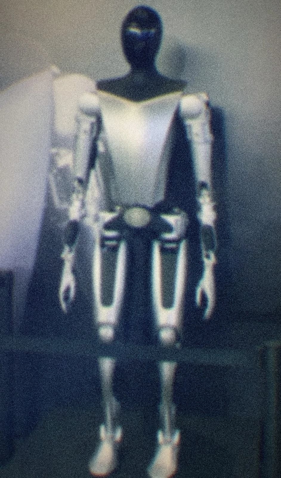 Sleek modern humanoid robot, white/grey full-body figure standing against a plain backdrop, portrait orientation