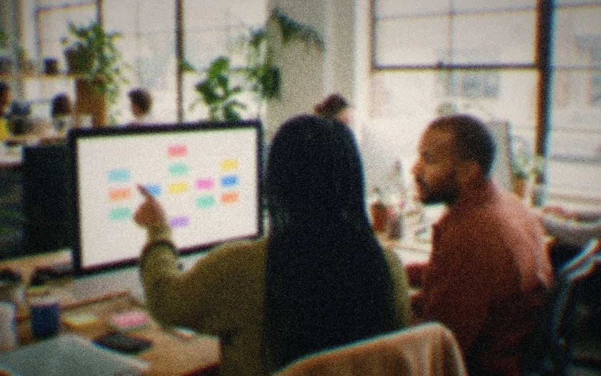 Two colleagues, seen from behind, working through a learning module on a laptop