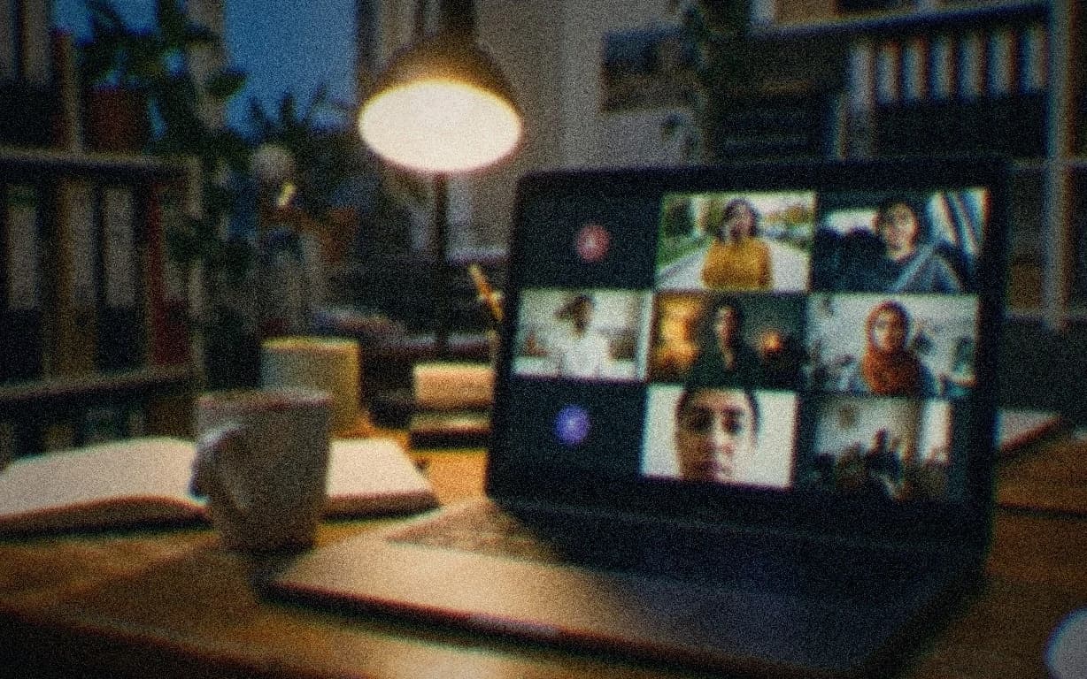 A laptop showing a company all-hands video call, one colleague per tile