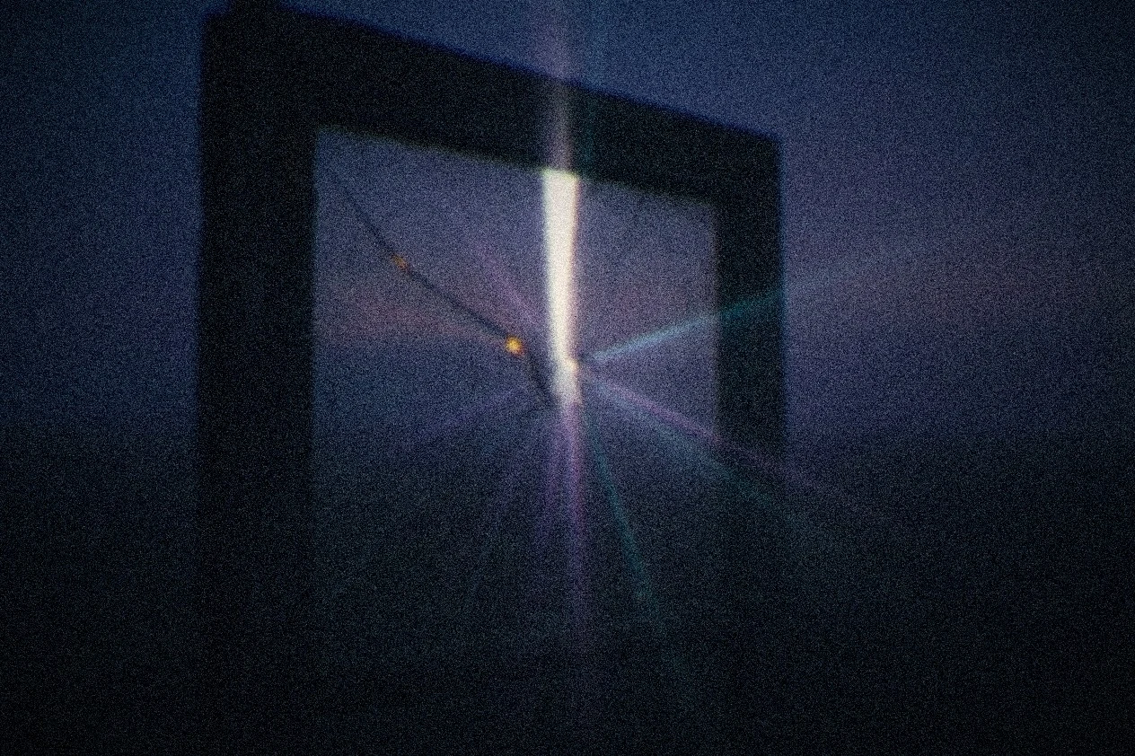 A beam of light passing through a cracked, weathered pane of glass, scattering unevenly through the fracture, most of it lost to shadow, a few thin beams making it through.